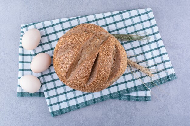 밀은 계란과 빵 덩어리를 대리석 표면에 접힌 수건에 놓았습니다.