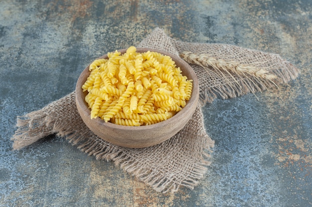 Free photo wheat with a bowl of pasta on the towel, on the marble surface.