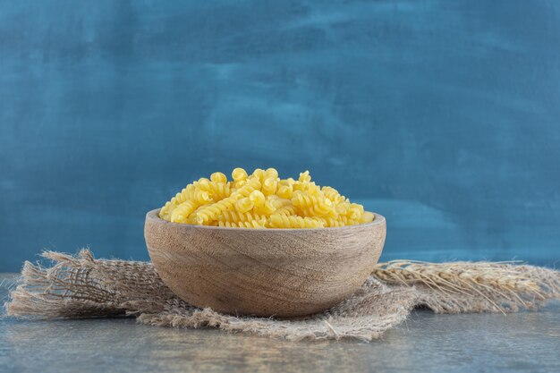 Wheat with a bowl of pasta on the towel, on the marble surface.