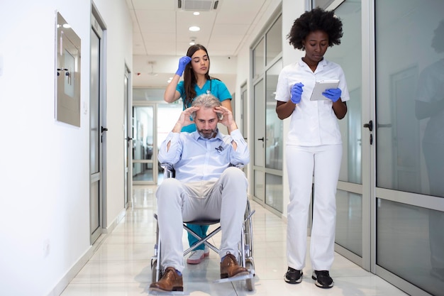 Wheelchair patient with professional African American female doctor and nurse specialist staff in corridor of hospital recovery center