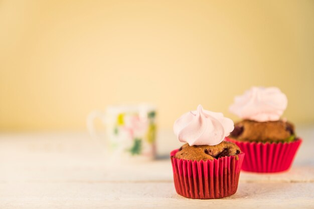 Whipped cream on muffins in the red paper holder