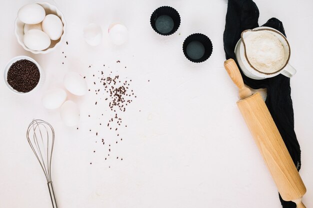 Whisk and rolling pin near pastry ingredients