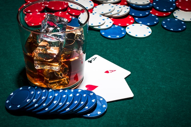 Whisky glass with ice cubes over the gambling table