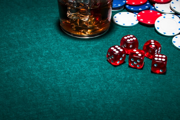 Free photo whisky glass with ice cubes over the gambling table