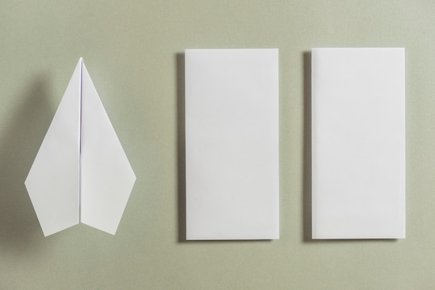 White airplane besides two folded papers on bright background