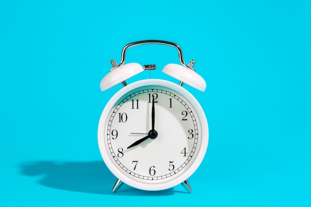 White alarm clock on a blue background isolated closeup