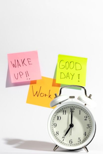 Free photo white alarm clock and colored paper reminders on white background