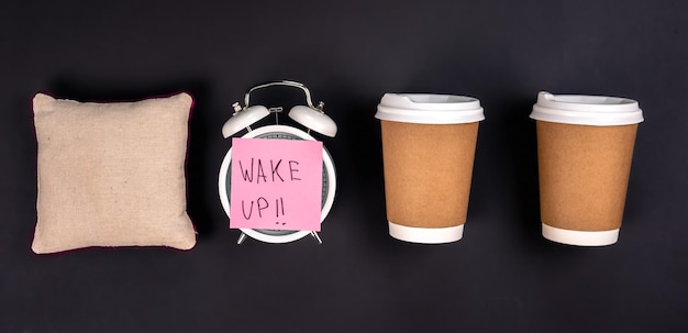 Free photo white alarm clock disposable cups and a small pillow on a dark background