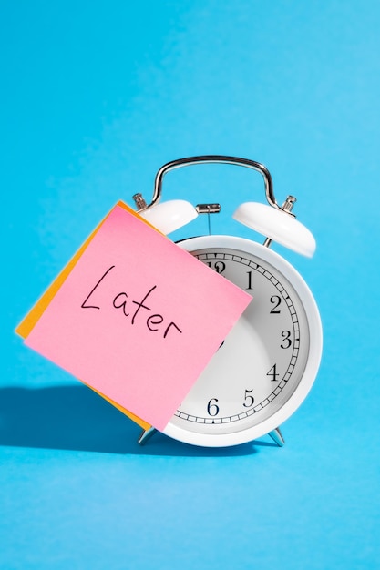 Free photo white alarm clock and sticker with the inscription late on a blue background