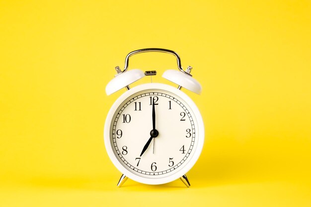 White alarm clock on a yellow background isolated closeup