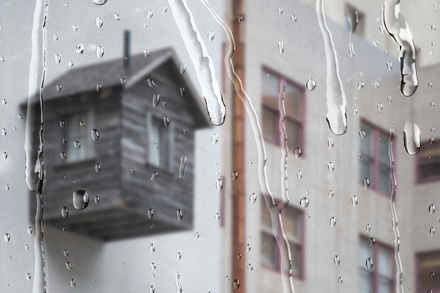 Белая квартира через окно с каплями дождя