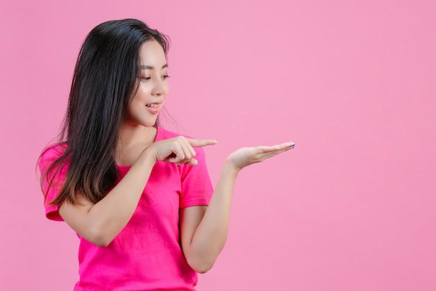 백인 아시아 여자 오른손은 오른손을 잡고 있던 왼손을 가리 켰습니다. 분홍색에.