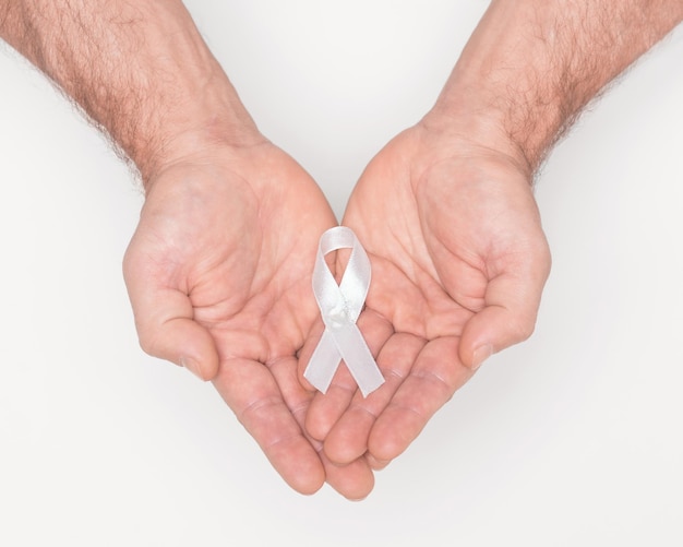 White awareness ribbon Lung cancer awareness white ribbon bow on man hands Anti violence against women Medical and political awareness symbol Healthcare concept Political movement concept