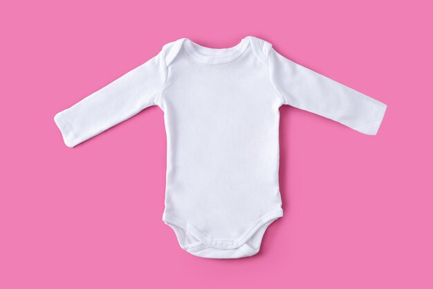 White baby clothes on pink background Copy space