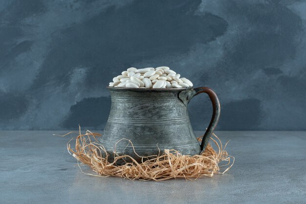 White beans in a metallic ethnic pot on dry grasses. High quality photo