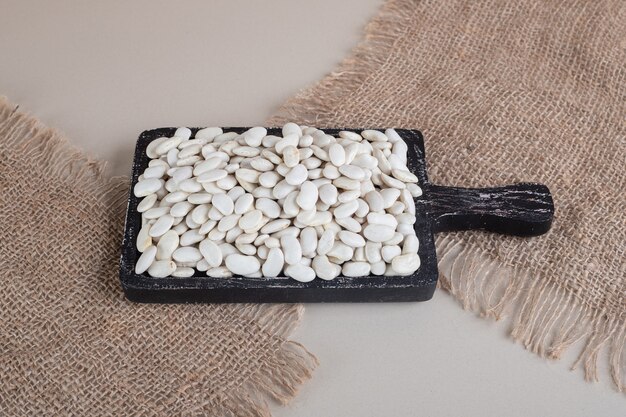 White beans on a piece of board on concrete.