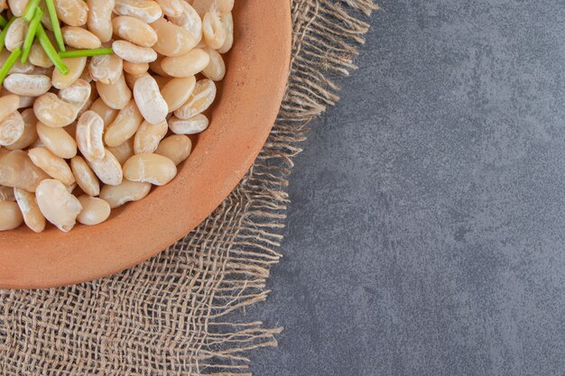 White beans on a plate on the burlap napkin on the marble surface