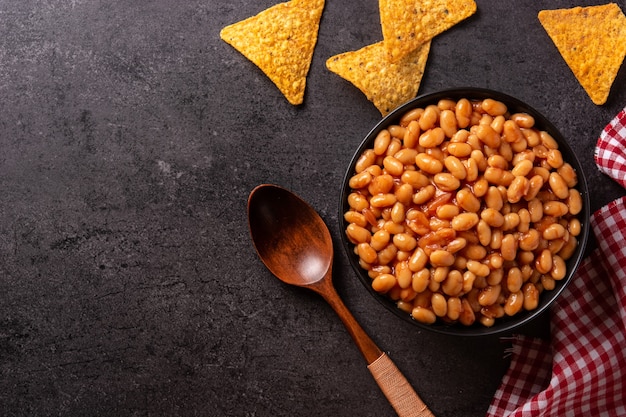 Free photo white beans in tomato sauce in bowl on black stone