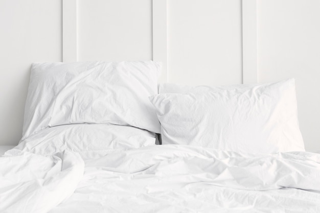 White bed linen on a bed in a white bedroom