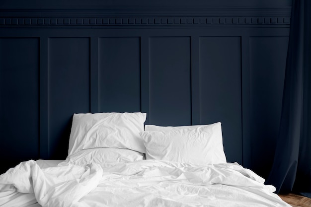 Белое постельное белье на матрасе в темно-синей спальне
