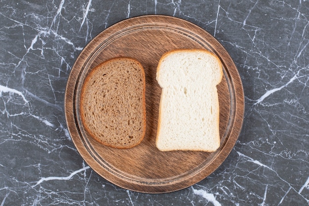 Free photo white and black bread on the board , on the marble surface