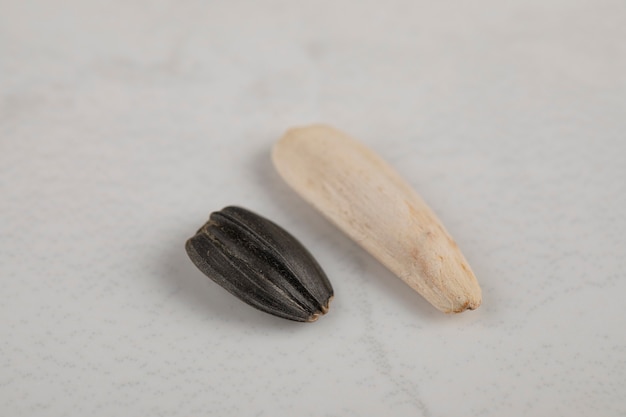 White and black sunflower black seeds placed on white surface 