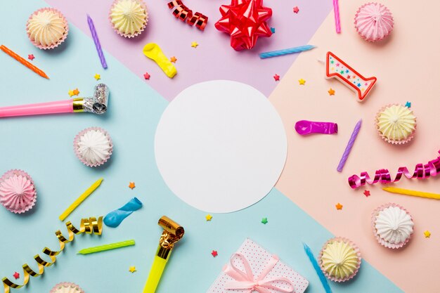 White blank circle frame surrounded with aalaw; sprinkles; streamers; balloon and candles on colored backdrop