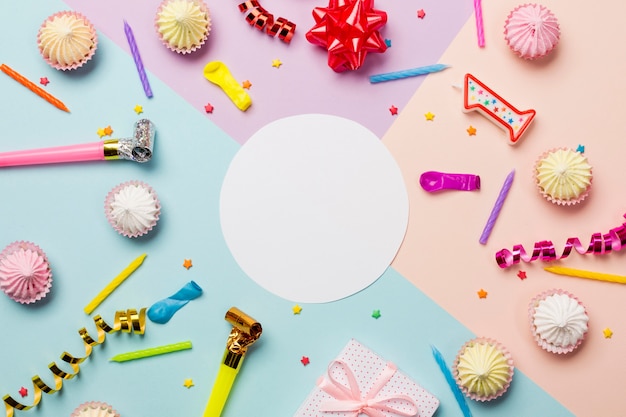 White blank circle frame surrounded with aalaw; sprinkles; streamers; balloon and candles on colored backdrop