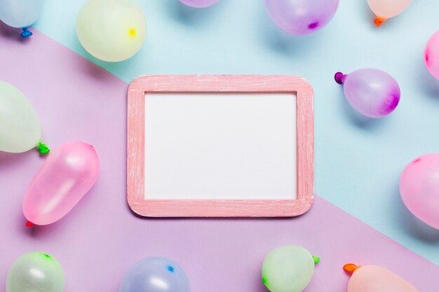 White blank frame decorated with balloons on blue and pink background