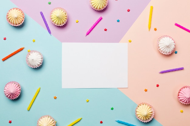 White blank paper surrounded with candles; sprinkles; aalaw on colored backdrop