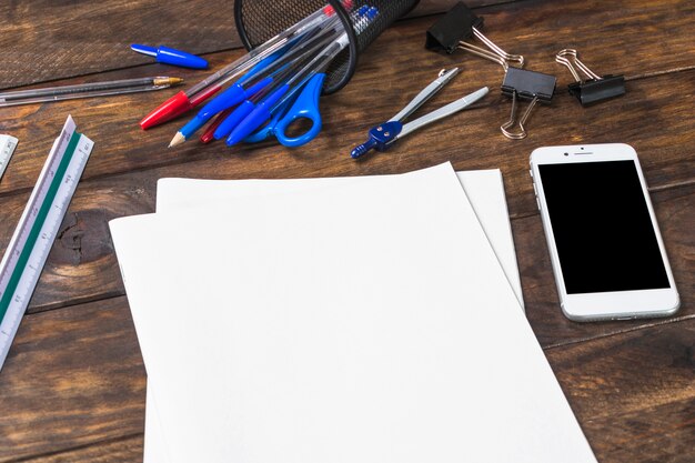 White blank paper with stationeries and smartphone on wooden table