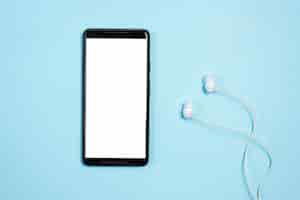 Free photo white blank screen display on mobile phone with earphones against blue background