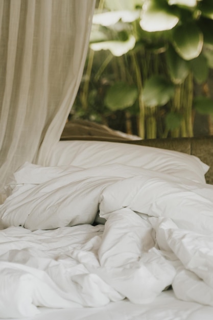 White blanket and pillow with palm trees background in tropical Bali style