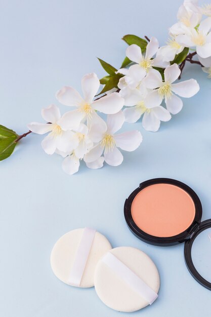 White blossoms; two sponges and blusher on blue background