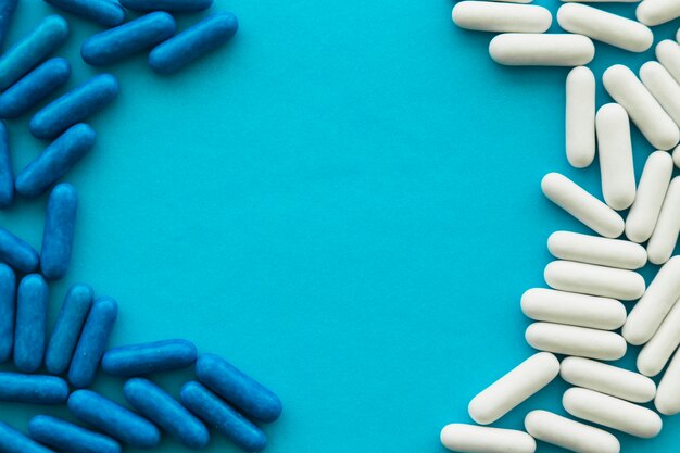 White and blue candy capsules forming frame on cyan background