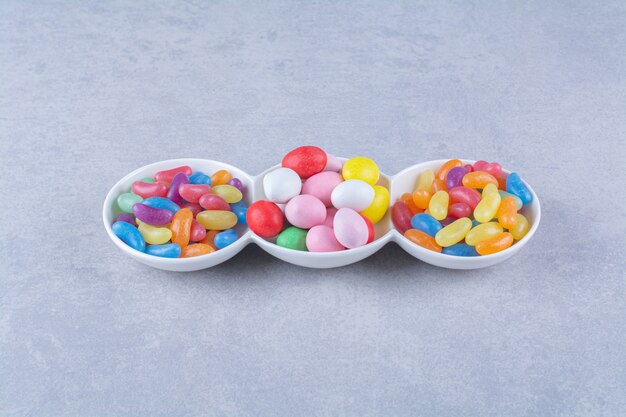 A white board full of colorful bean candies on gray table. 