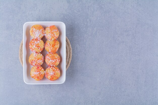 A white board of round yellow cookies with sprinkles. 