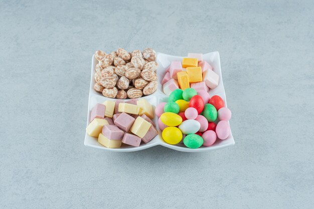 A white board with marshmallows and colorful candies on white surface