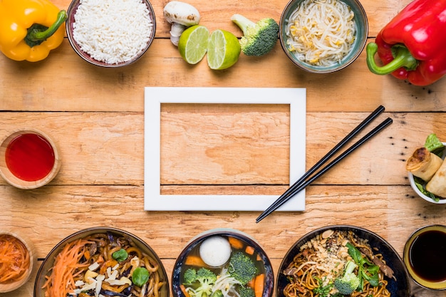 Free photo white border frame with chopsticks and thai traditional food on wooden desk