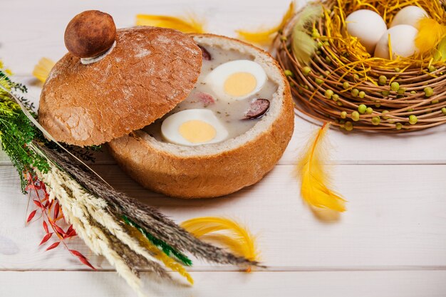 Free photo white borscht in bread on wood table