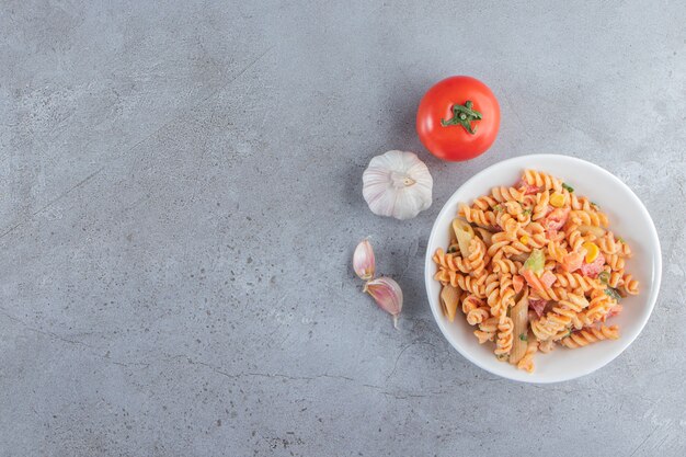 White bowl of delicious fusilli pasta on stone background. 