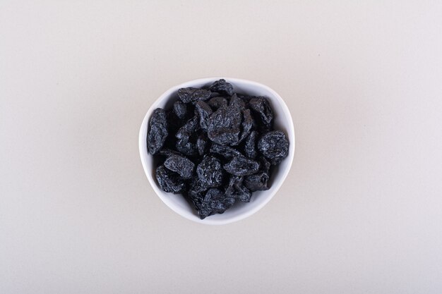 White bowl of dried plum fruits placed