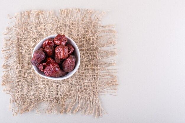 White bowl of dried tasty silverberry fruits on white background. High quality photo