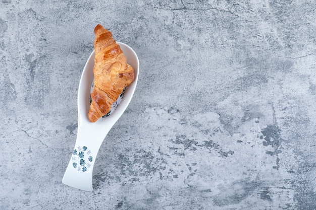 Foto gratuita una ciotola bianca di croissant freschi su un tavolo di pietra.