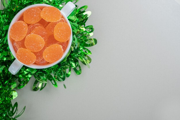 A white bowl full of sugary orange marmalades .