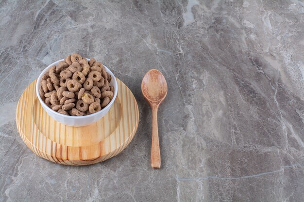 A white bowl of healthy chocolate cereal rings for breakfast .