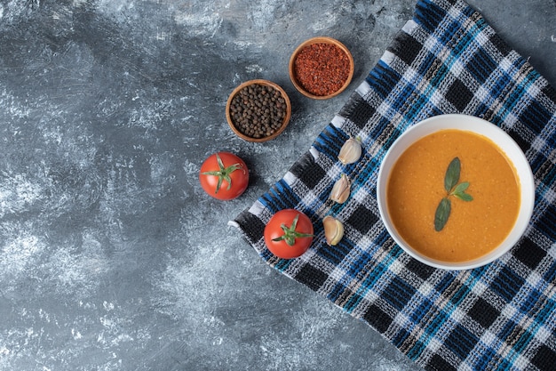 Una ciotola bianca di zuppa di lenticchie con verdure su una bella tovaglia.