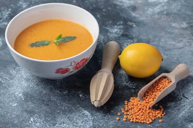 A white bowl of lentil soup with a wooden reamer.