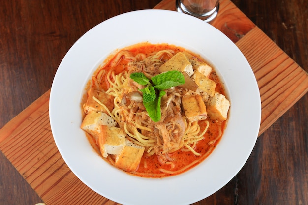 Белая тарелка супа со спагетти и кусочками хлеба, украшенными зеленью