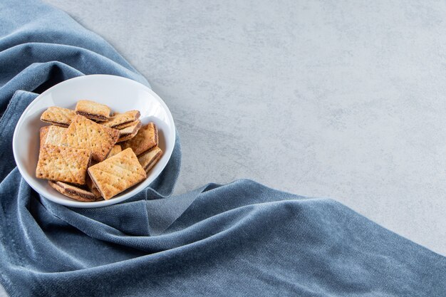 White bowl of tasty crunchy crackers on stone.